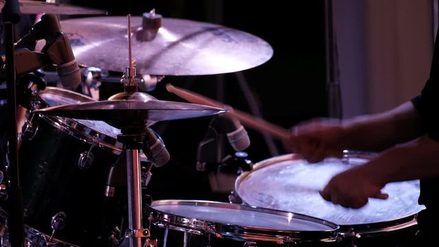 Close-up of the hands of a drummer beating sticks on cymbals of an drum kit. Concert performance of a rock band, jazz band or symphony orchestra. Drum set.