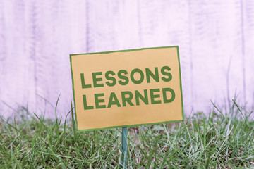 Handwriting text writing Lessons Learned. Conceptual photo the knowledge or understanding gained by experience Plain empty paper attached to a stick and placed in the green grassy land