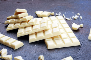 white broken chocolate and cocoa bar. Pieces of white chocolate on rustic background