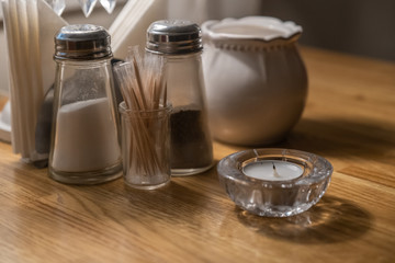 Salt shaker, pepper shaker, toothpicks and a candle on a table in a cafe