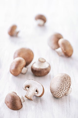 Fresh royal champignon mushrooms on a white wooden table. High key image. Vertical orientation, shallow depth of field
