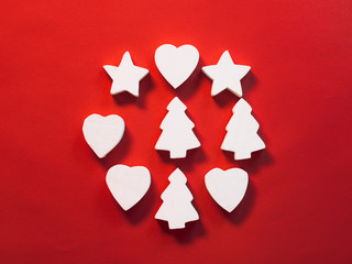 Christmas holiday concept. Abstract wreath of white stars, hearts and fir trees on red background. Copy space.