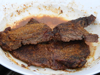 Steak well-done on white plate cooked in a microwave oven