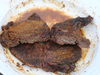 Steak well-done on white plate cooked in a microwave oven