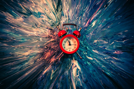 Time travel concept. Red vintage alarm clock on smeared blue and white paint. Abstract art background.