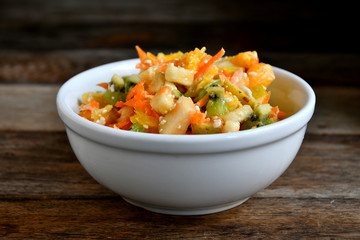 Fruit salad in a white bowl on a wooden table.