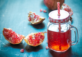 Fresh ripe pomegranate and glasses of pomegranate juice on blue wooden table 