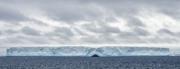 Fototapeta na wymiar Wide shot of a tabular iceberg in Antarctica under cloudy sky