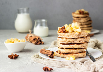 Stack of delicious sweet and spicy apple pancakes with fried caramelized apples and spices (anise and cinnamon) on a white plate. Autumn breakfast. 