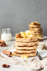 Stack of delicious sweet and spicy apple pancakes with fried caramelized apples and spices (anise and cinnamon) on a white plate. Autumn breakfast. 