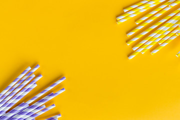 Celebration pattern flat lay,holiday celebration drinking cocktail party straws.Template for greeting card,design.Eco,reusable, paper, striped straw for drinking juice or cocktail on yellow background