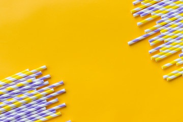 Celebration pattern flat lay,holiday celebration drinking cocktail party straws.Template for greeting card,design.Eco,reusable, paper, striped straw for drinking juice or cocktail on yellow background