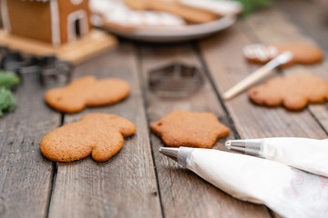 Fototapeta na wymiar Christmas homemade gingerbread cookies on wooden table. Icing of Christmas bakery. closeup, copy space. Blank biscuit gingerbread house, ready to decorate.