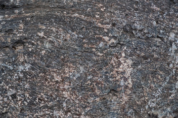 Texture, stone it can be used as a background.  Fragment of a multi-colored stone with scratches and cracks.