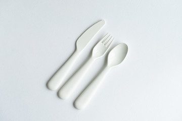 Colored bright plastic dishes beautifully laid out on a white background. Knives, forks, spoons. Menu concept for bar and restaurant. Free space for text. 