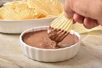 Dipping a potato chip into melted chocolate
