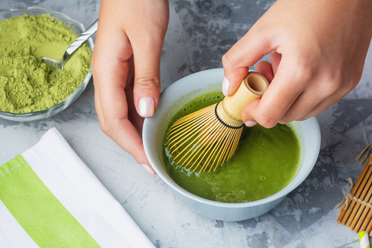 Girl stirs matcha green tea a bamboo whisk. The process of making tea close-up.