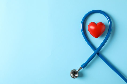 Stethoscope and heart on blue background, top view