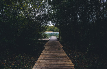 The wooden boat dock is surrounded by trees. Recreation for tourists who are brought by boat to the lake on the water.
