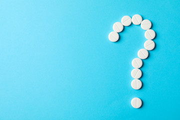 Question mark layd out of pills on blue background, space for text
