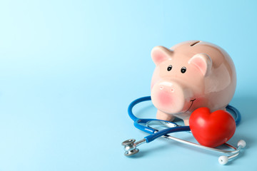 Stethoscope and piggy bank on blue background, space for text