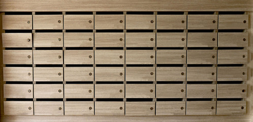 Closeup of unnumbered mailboxes and lockers in raw in the condo. Natural wooden letterbox panel pattern .