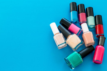 Obraz premium Choose nail polish. Polish bottels on blue background top view copy space