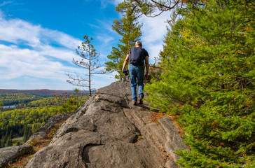 Obraz premium Back View of a Man Climbing up a Steep Cliff
