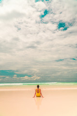 Yellow bikini Woman on beach. Tourist walking along Tropical Galapagos beach with turquoise ocean waves and white sand. Holiday, vacation, paradise, summer vibes. Isabela, San Cristobal