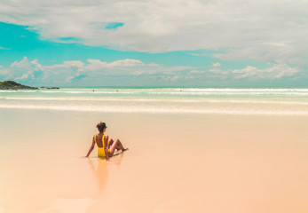 Yellow bikini Woman on beach. Tourist walking along Tropical Galapagos beach with turquoise ocean...
