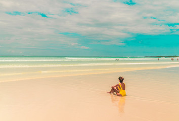 Yellow bikini Woman on beach. Tourist walking along Tropical Galapagos beach with turquoise ocean waves and white sand. Holiday, vacation, paradise, summer vibes. Isabela, San Cristobal