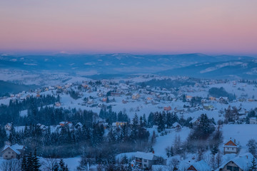 Small wooden village in mountains covered by snow.