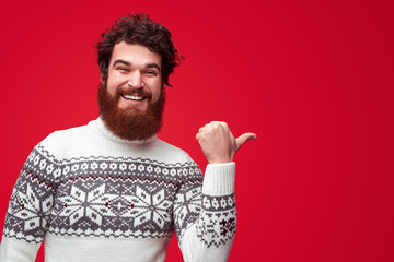 Cheerful bearded guy pointing aside