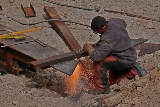 Bauarbeiter kniend mit Schweißgerät und Schutzkleidung