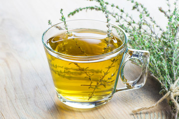 glass cup of healthy herbal thyme tea with fresh thyme leaves bunch on wooden rustic background, hot drink thymus 