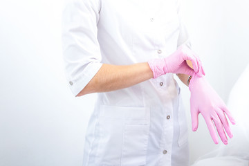 doctor puts pink rubber gloves on his hand