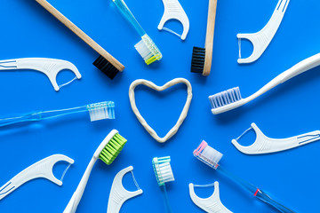 Oral hygiene concept. Heart drawn with toothpaste near toothbrushes on blue background top view