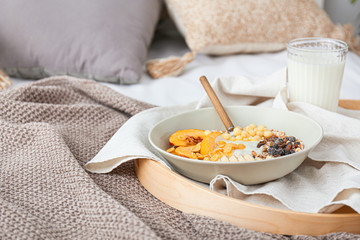 Tray with tasty breakfast on bed