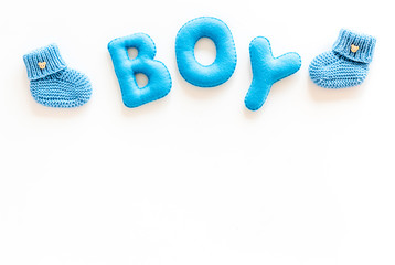 Children's birthday concept. Word boy near booties on white background top view frame copy space
