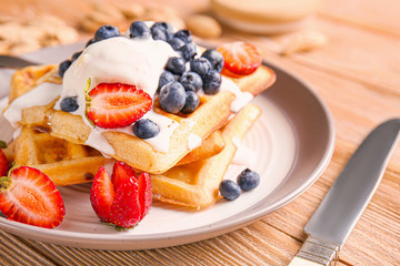 Tasty waffles with ice-cream and berries on plate, closeup