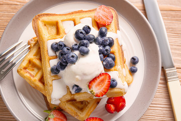 Tasty waffles with ice-cream and berries on plate, closeup