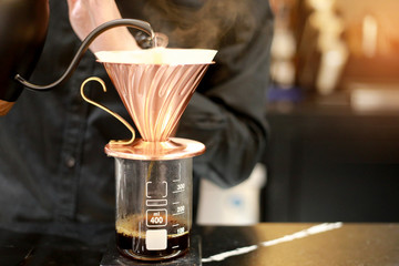 Barista brewing drip coffee with hot water pot with smoke and hand. Drink concept. Dark tone.