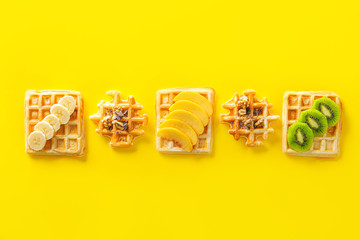 Sweet tasty waffles with chocolate and fruits on color background