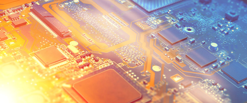 Closeup on electronic motherboard in hardware repair shop, blurred panoramic image with details of the circuitry and close-up on electronics. Picture toned in orange and blue.