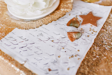 New Year mood, Christmas tree. Rectangular table covered with a gold tablecloth, decorated with candles with flowers for celebration. Festive still life by candlelight.