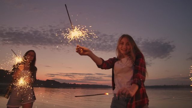 Beautiful Women In Summer With Sparklers Dancing In Slow Motion On The Beach At Night.