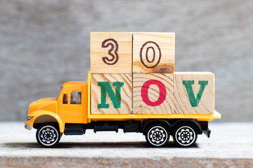 Truck hold letter block in word 30nov on wood background (Concept for date 30 month November)