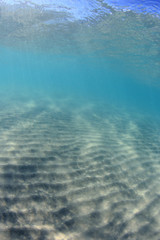 Underwater background of clear blue water on sandy sea floor