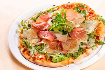 Italian Cuisine. Pizza with prosciutto, ham, arugula and parmesan