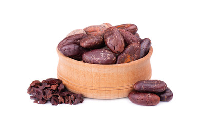 Peeled cocoa beans in the wooden bowl, isolated on white background. Roasted and aromatic cocoa beans, natural chocolate.